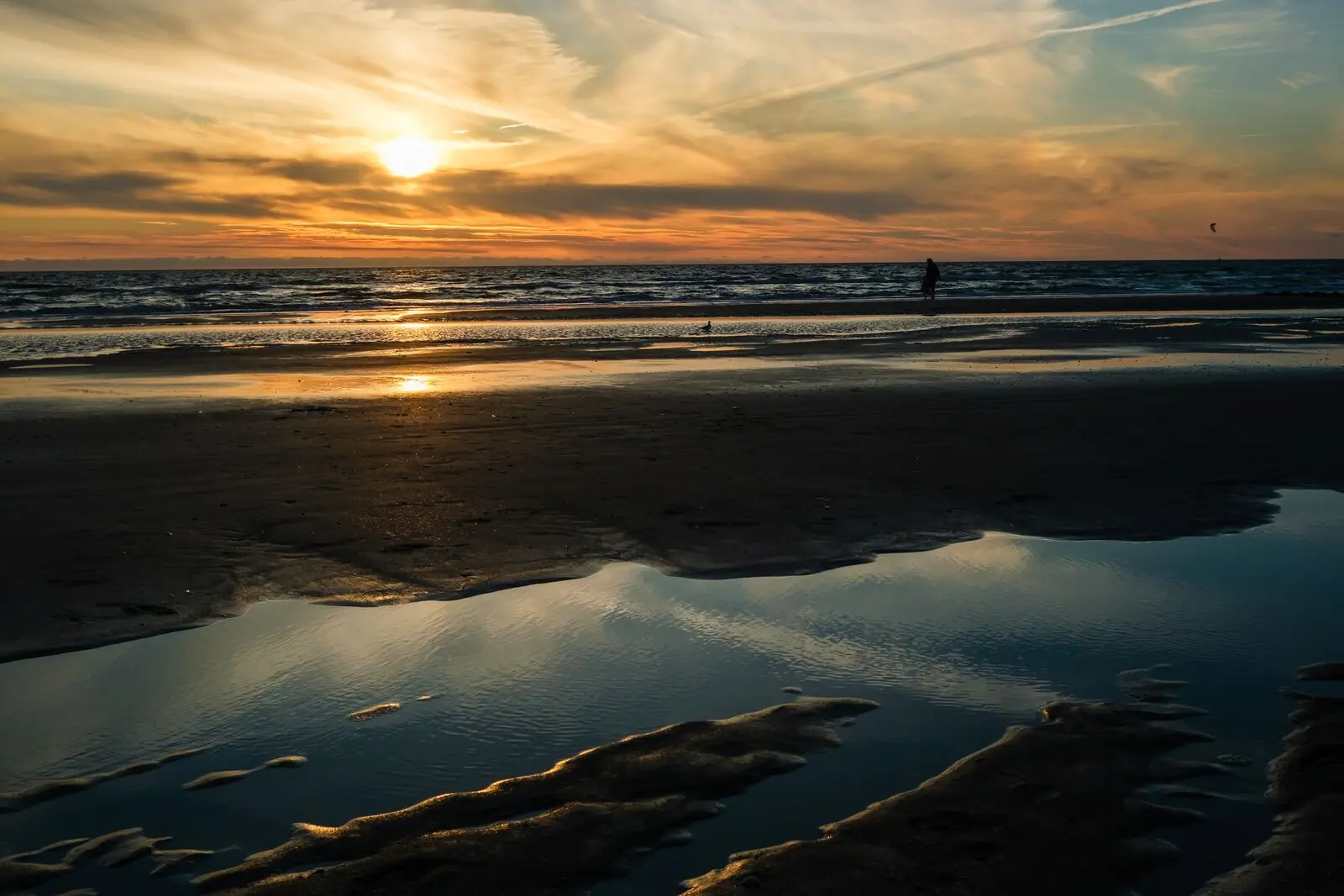 Low sun over wet sand and tide pools on a Baltic beach