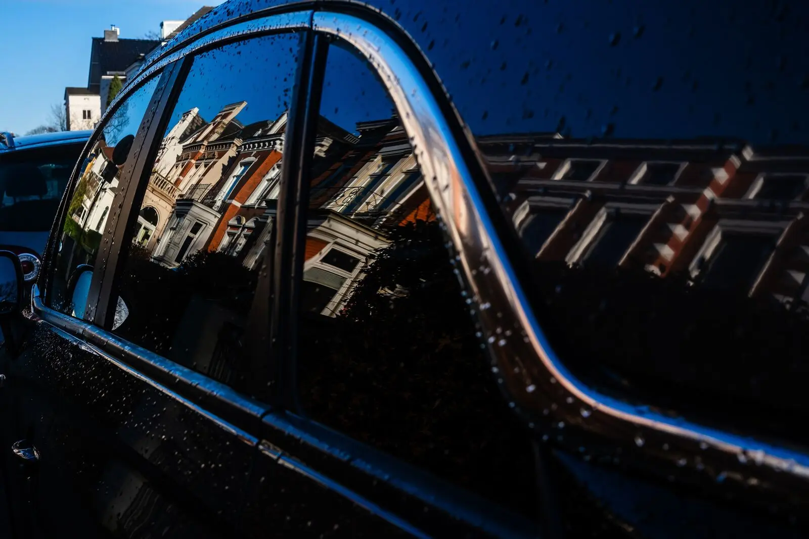 Old town houses reflected in a rain-specked car window