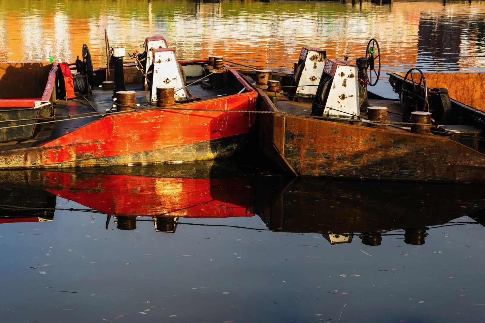 Red work barges mirrored in still harbour water