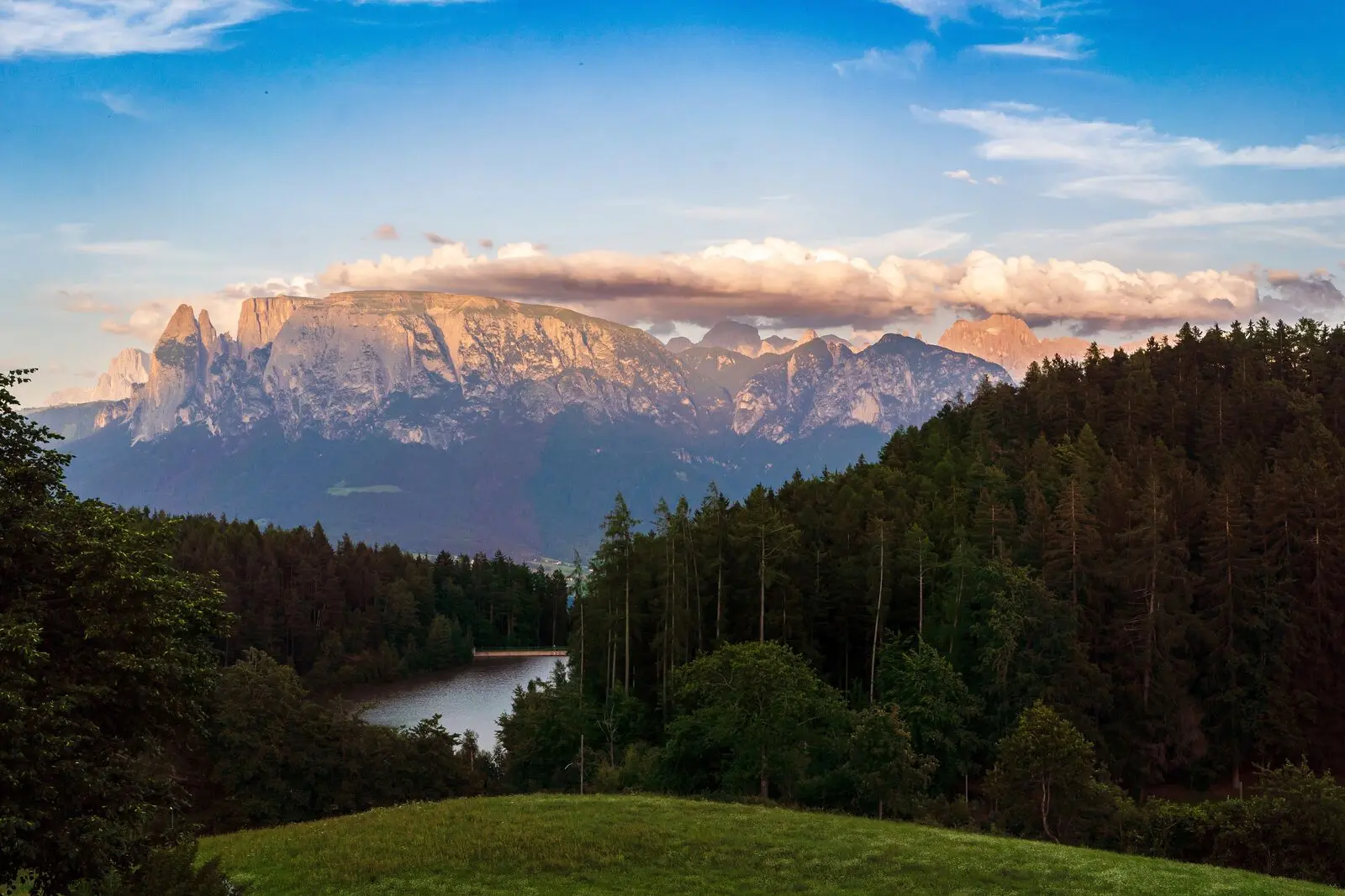 A forest lake below a cloud-capped mountain range