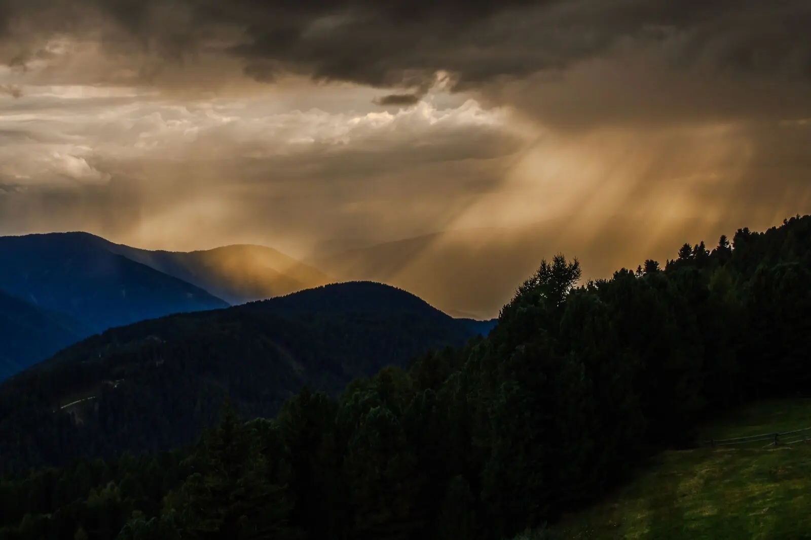 Sun rays breaking through clouds over dark mountain ridges