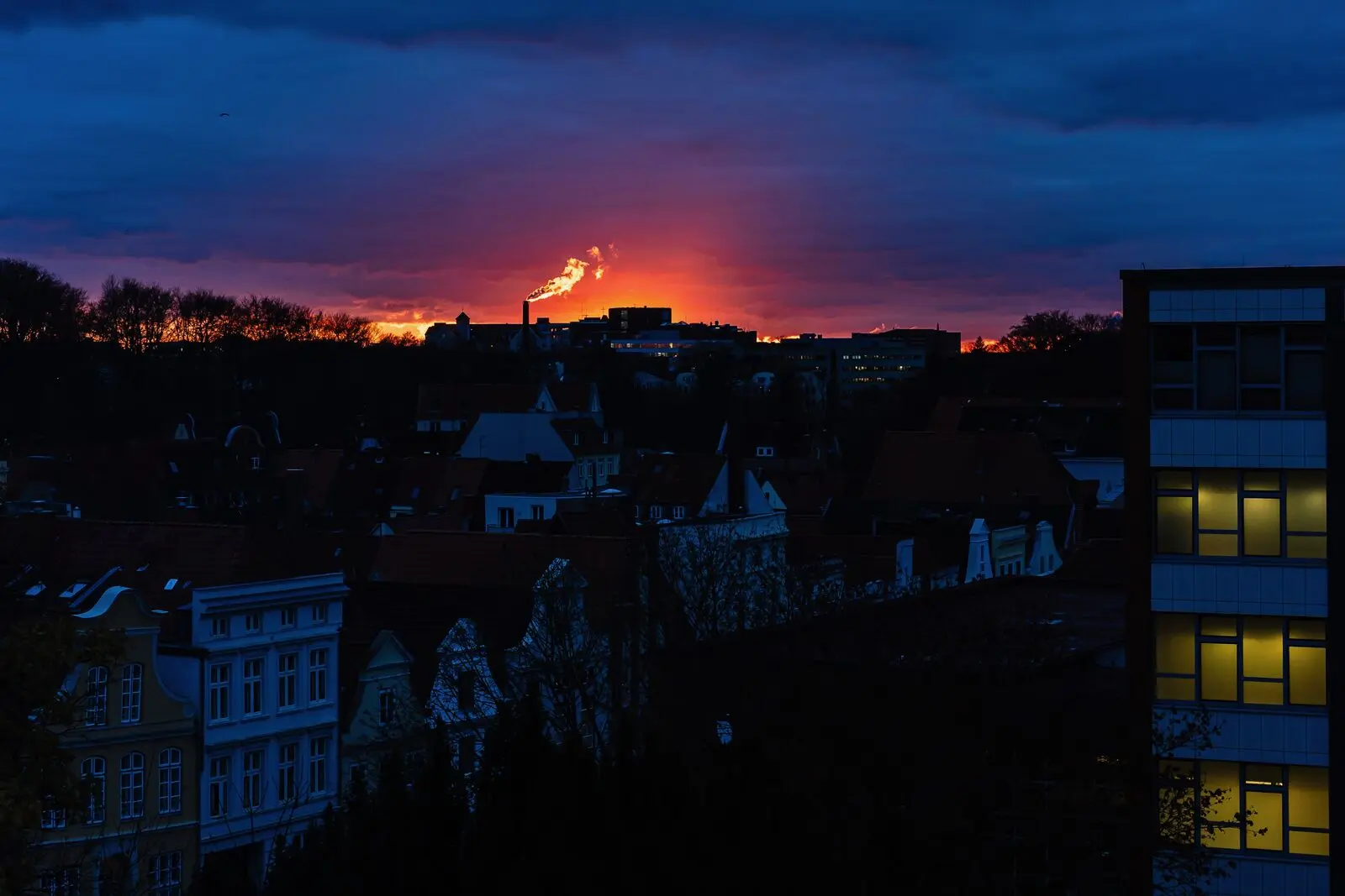 Lübeck rooftops at dusk with a red glow on the horizon